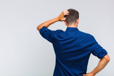 Genç yakışıklı bir adam bilgisiz ve kafası karışık hissediyor, bir çözüm düşünüyor, eli kalçasında, diğeri kafasında, dikiz aynasından.