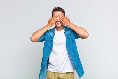 Genç yakışıklı adam gülümsüyor ve mutlu hissediyor, iki eliyle gözlerini kapatıyor ve inanılmaz bir sürpriz bekliyor.