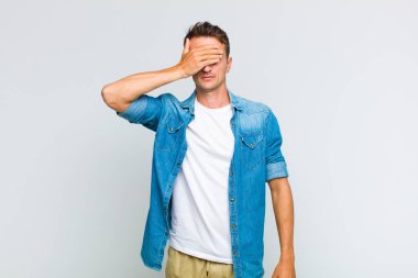 Genç yakışıklı bir adam tek eliyle gözlerini kapatıyor. Korkmuş ya da endişeli, merak ediyor ya da körü körüne bir sürpriz bekliyor.