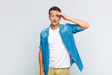 Genç yakışıklı adam mutlu, şaşkın ve şaşırmış görünüyor, gülümsüyor ve inanılmaz ve inanılmaz iyi haberleri fark ediyor.