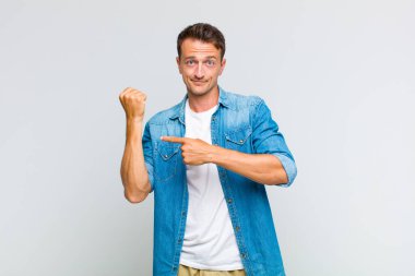 Genç yakışıklı adam sabırsız ve kızgın görünüyor, saati gösteriyor, dakiklik istiyor, zamanında gelmek istiyor.