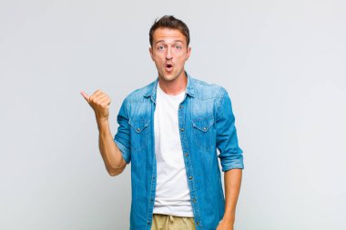 Genç ve yakışıklı adam inançsızlıktan şaşkın şaşkın bakıyor, yan taraftaki objeyi işaret ediyor ve diyor ki vay canına, inanılmaz.