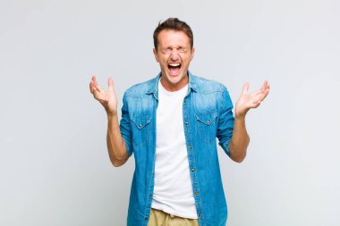 Genç yakışıklı adam öfkeyle bağırıyor, stresli hissediyor ve ellerini havaya kaldırıp neden ben diye bağırıyor.