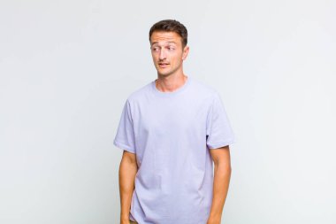 Genç yakışıklı adam şok olmuş, mutlu, şaşkın ve şaşırmış hissediyor, ağzı açık bir şekilde yana bakıyor.