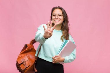 Genç İspanyol kadın gülümsüyor ve arkadaş canlısı görünüyor. Elleri önde, geriye doğru sayıyor.