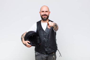 Kel adam kameraya bakıyor, tatmin olmuş, kendinden emin, dostane bir gülümsemeyle, seni seçiyor.