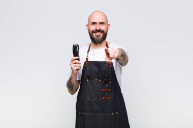 Kel adam kameraya bakıyor, tatmin olmuş, kendinden emin, dostane bir gülümsemeyle, seni seçiyor.