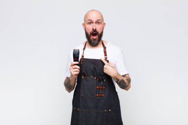 Şok olmuş ve ağzı açık, kendini işaret eden kel bir adam.