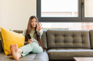 Genç Asyalı kadın gülümsüyor ve arkadaş canlısı görünüyor. Elleri önde, geriye doğru sayıyor.