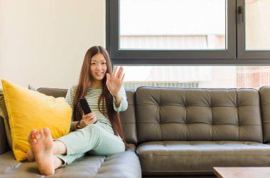 Genç Asyalı kadın gülümsüyor ve arkadaş canlısı görünüyor, 5 ya da 5 numarayı gösteriyor, eli önde, geri sayıyor.