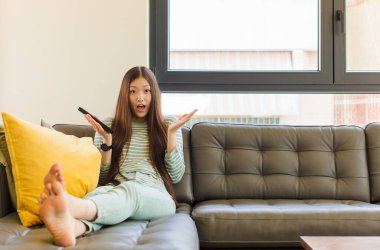 Genç Asyalı kadın şok olmuş ve şaşırmış, endişeli ve paniklemiş, stresli ve dehşete kapılmış bir bakışla