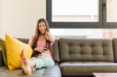 Genç Asyalı kadın kameraya tatmin olmuş, kendinden emin, dost canlısı bir gülümsemeyle bakıyor ve seni seçiyor.