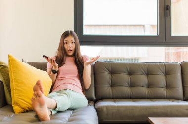 Genç Asyalı kadın şok olmuş ve şaşırmış, endişeli ve paniklemiş, stresli ve dehşete kapılmış bir bakışla