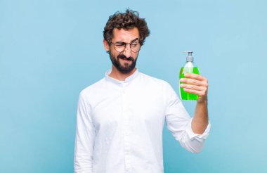 Genç sakallı adam üzgün, üzgün ya da kızgın ve olumsuz bir tavır takınıyor, anlaşmazlıkla kaşlarını çatıyor.