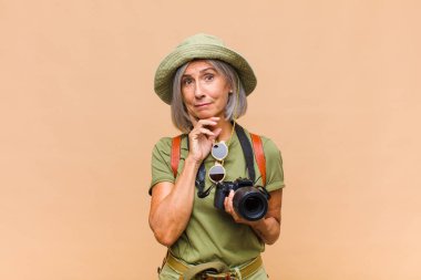 Orta yaşlı bir kadın mutlu bir şekilde gülümsüyor ve hayal kuruyor ya da şüphe ediyor.