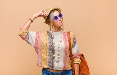 Orta yaşlı kadın şaşkın ve şaşkın hissediyor, kafasını kaşıyor ve yan tarafa bakıyor.