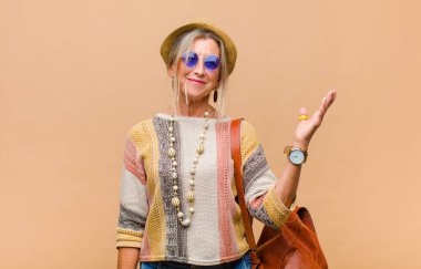 Orta yaşlı bir kadın mutlu, şaşırmış ve neşeli, pozitif bir tavırla gülümsüyor, bir çözüm ya da fikir buluyor.