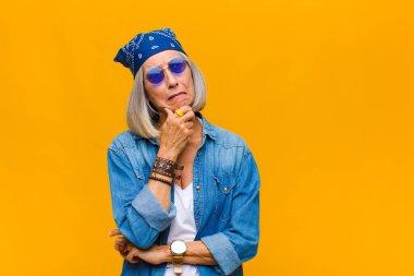 Orta yaşlı kadın düşünüyor, kuşkulu ve şaşkın hissediyor, farklı seçeneklerle, hangi kararı vereceğini merak ediyor.