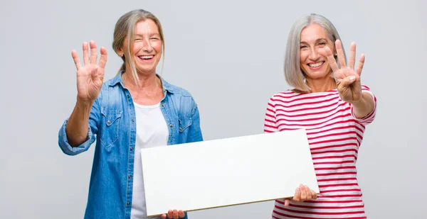 Vrouw Van Middelbare Leeftijd Lacht Ziet Vriendelijk Uit Toont Nummer — Stockfoto