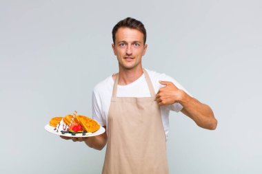 Genç yakışıklı adam mutlu, şaşkın ve gururlu, heyecanlı, şaşkın bakışlarıyla kendini işaret ediyor.