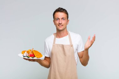 Genç yakışıklı adam kendini mutlu, şaşırmış ve neşeli hissediyor. Pozitif bir tavırla gülümsüyor. Bir çözüm ya da fikir buluyor.