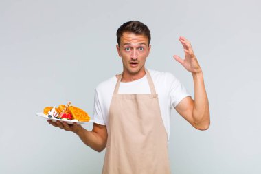 Genç yakışıklı adam elleri havada bağırıyor, öfkeli, sinirli, stresli ve üzgün hissediyor.