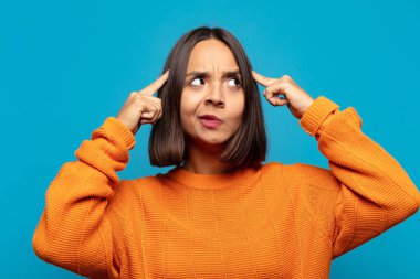 Hispanik kadın kafası karışık ya da şüpheci, bir fikre odaklanmış, çok düşünüyor, kenarda boşluklar arıyor.