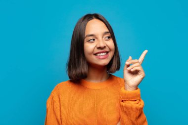 İspanyol kadın mutlu bir şekilde gülümsüyor ve yan bakıyor, merak ediyor, düşünüyor ya da bir fikri var.