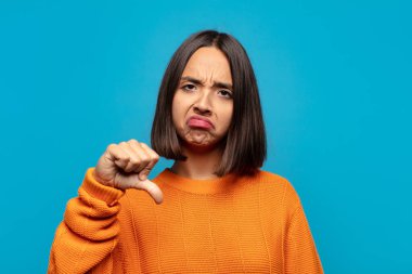 Hispanik kadın kızgın, sinirli, hayal kırıklığına uğramış ya da hoşnutsuz, ciddi bir bakışla başparmaklarını göstermiyor.