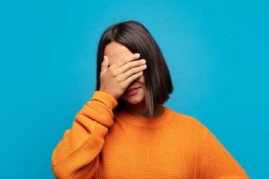 İspanyol kadın stresli, utanmış ya da üzgün görünüyor, baş ağrısı var, yüzünü elleriyle kapatıyor.
