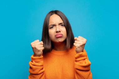 İspanyol kadın kendinden emin, sinirli, güçlü ve agresif görünüyor. Yumrukları boks pozisyonunda dövüşmeye hazır.