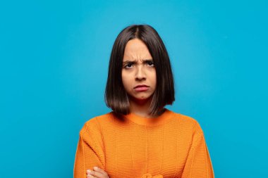 İspanyol kadın hayal kırıklığına uğramış, hayal kırıklığına uğramış, ciddi görünüyor, sinirlenmiş ve kollarını kavuşturmuş.