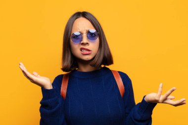 İspanyol kadın şaşkın, şaşkın ve stresli görünüyor, farklı seçenekler arasında merak ediyor, kararsız hissediyor.