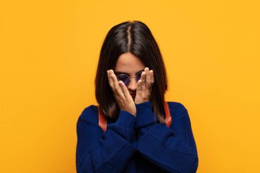 Hispanik kadın üzgün, hayal kırıklığına uğramış, gergin ve depresif, iki eliyle yüzünü kaplayan, ağlayan