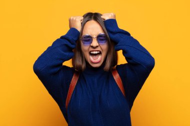 İspanyol kadın stresli ve endişeli, depresif ve hayal kırıklığına uğramış hissediyor, iki elini de başa kaldırıyor.