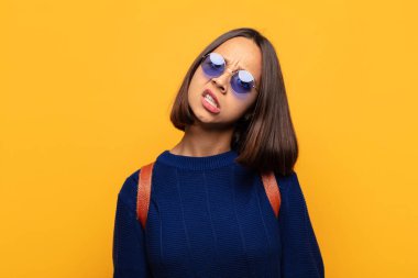 hispanic woman feeling puzzled and confused, with a dumb, stunned expression looking at something unexpected