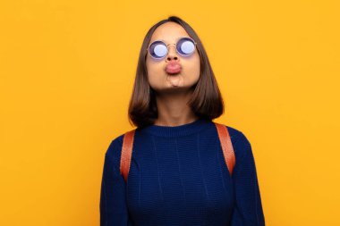 Tatlı, eğlenceli, mutlu, sevimli bir yüz ifadesiyle dudaklarını birbirine bastıran İspanyol kadın öpücük yolluyor.