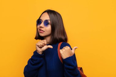 İspanyol kadın neşeli bir şekilde gülümsüyor ve yan taraftaki fotokopi alanını gösteriyor, mutlu ve tatmin olmuş hissediyor.