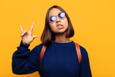 İspanyol kadın kendini mutlu, eğlenceli, kendinden emin, pozitif ve asi hissediyor, elle rock veya heavy metal işareti yapıyor.