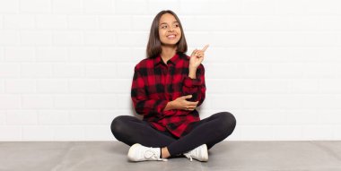 İspanyol kadın mutlu bir şekilde gülümsüyor ve yan bakıyor, merak ediyor, düşünüyor ya da bir fikri var.