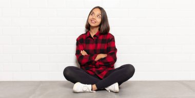 İspanyol kadın kendini mutlu, gururlu ve umutlu hissediyor, merak ediyor ya da düşünüyor, çapraz kollarla boşluğu doldurmaya çalışıyor.