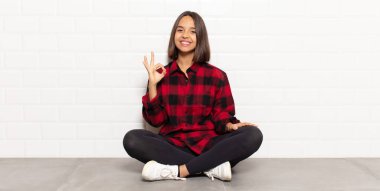 İspanyol kadın kendini mutlu, rahat ve tatmin olmuş hissediyor. Onayını iyi bir hareketle gösteriyor. Gülümsüyor.