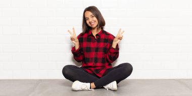 İspanyol kadın gülümsüyor ve mutlu görünüyor, arkadaş canlısı ve memnun, işaret ediyor zafer ya da barış iki elle