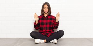 İspanyol kadın ciddi, mutsuz, kızgın ve hoşnutsuz görünüyor. Girmeyi yasaklıyor ya da her iki avuçta da dur diyor.