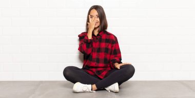 İspanyol kadın elleriyle yüzünü kapatıyor, parmaklarının arasından şaşkın bir ifadeyle yan tarafa bakıyor.