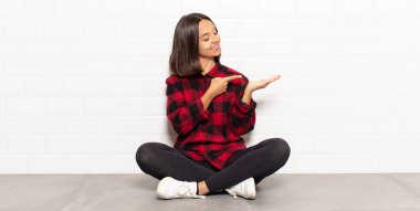 İspanyol kadın gülümsüyor, mutlu, kaygısız ve tatmin olmuş hissediyor, fotokopi alanındaki konsepte ya da fikre işaret ediyor.