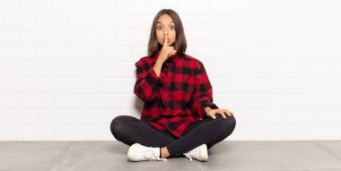 İspanyol kadın ciddi görünüyor ve parmaklarını dudaklarına bastırıp sessizlik ya da sessizlik talep ediyor, sır saklıyor.