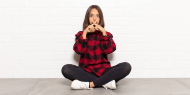 İspanyol kadın ciddi ve hoşnutsuz görünüyor. İki parmağının önde olması reddedilerek sessizlik istiyor.