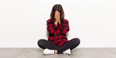 Hispanik kadın üzgün, hayal kırıklığına uğramış, gergin ve depresif, iki eliyle yüzünü kaplayan, ağlayan