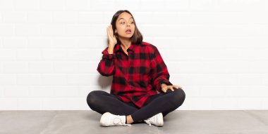 İspanyol kadın gülümsüyor, tuhaf bir şekilde yan tarafa bakıyor, dedikoduları dinlemeye ya da bir sırrı duymaya çalışıyor.